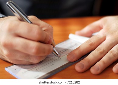 Closeup On Man`s Hands Writing A Check