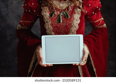 Closeup on medieval queen in red dress showing tablet PC blank screen on dark gray background. - Powered by Shutterstock