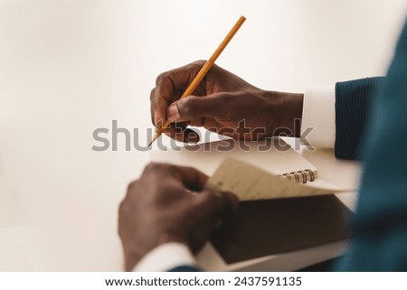 Close-up on note-taking: businessman's hands writing in a notepad during a corporate meeting - focus on effective note-taking.
