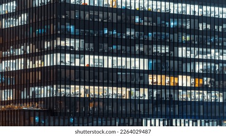 Close-up on an office building in the evening with some lightened workspaces. Modern, glazed skyscraper. Financial district. Late hours in the office. - Powered by Shutterstock