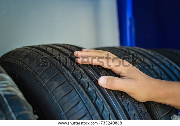 Closeup on\
person hand selecting new tire for modern car, abstract\
transportation technology background. Looking, buying, fixing,\
checking safety, manufacturing\
expertise
