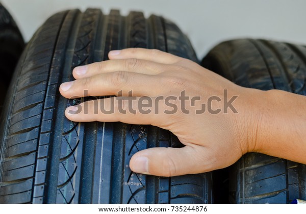 Closeup on\
person hand selecting new tire for modern car, abstract\
transportation technology background. Looking, buying, fixing,\
checking safety, manufacturing\
expertise