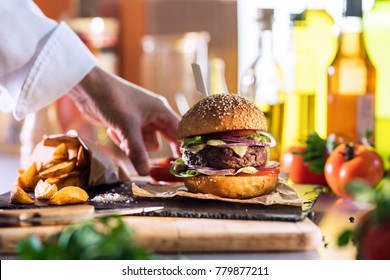 close-up on the preparation of a magnificent burger in a restaurant, the chef places a cup of ketchup near the potatoes. - Powered by Shutterstock