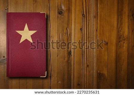 Close-up on a red book with a gilded star symbol in its middle.