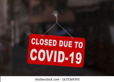 Close-up on a red closed sign in the window of a shop displaying the message 