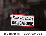 Close-up on a red and white sign in a window with written in French "Pass sanitaire obligatoire", meaning in English "Compulsory health pass".