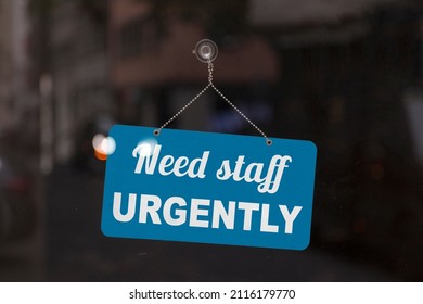 Close-up on a red and white sign in a window with written the message - Need staff urgently -. - Shutterstock ID 2116179770