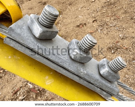 Close-up on robust galvanized nuts and bolts securing a guy wire to a utility pole, highlighting essential infrastructure.