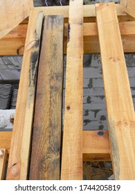A Close-up On Rotten, Damaged With Mold And Mildew Wood, Boards, Timber And New Untreated Timber Boards, Planks On A Brick House Construction.