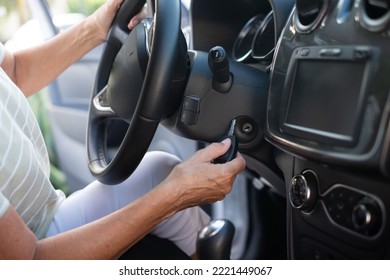 Close-up On Senior Woman In T-shirt Entering Her Car. With One Hand Woman Is Holding The Key And With Other The Steering Wheel.