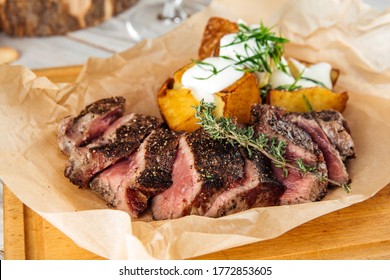 Closeup on sliced lumbar steak, thin sirloin with baked potatoes and sour cream, horizontal