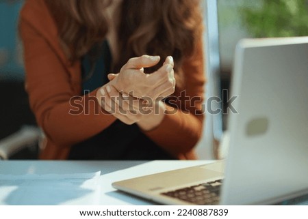 Closeup on small business owner woman with laptop experience carpal syndrome in the green office.