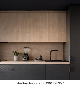 Close-up on small kitchen with dark and wooden cupboards, wooden countertop and backsplash