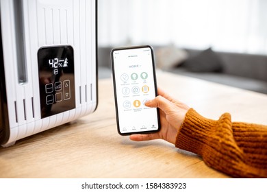 Close-up on a smart phone with launched home assistant application, controlling air humidifier at home - Shutterstock ID 1584383923