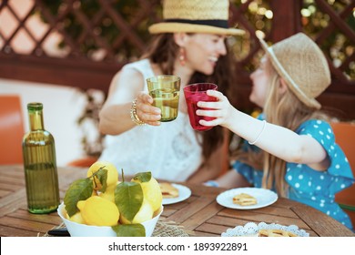 Closeup On Smiling Family With Green Bottle Of Lemonade And Plate Of Local Farm Lemons Clinking Glasses And Having Lunch In The Terrace Of Guest House Hotel.