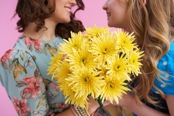 Closeup On Smiling Mother And Child With Long Wavy Hair With Yellow Chrysanthemums Flowers Isolated On Pink.
