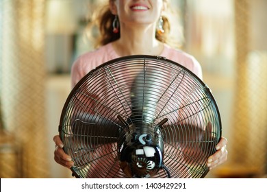 Closeup On Smiling Young Housewife In The Modern Living Room In Sunny Hot Summer Day Cooling Down In The Front Of Working Fan.