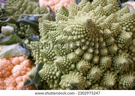 Close-up on a stack of cruciferous vegetables including romanesco broccolis and orange cauliflowers.