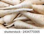 Close-up on a stack of Parsnips for sale on a market stall.