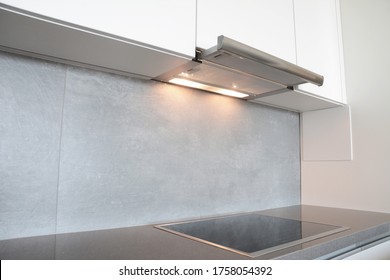 A Close-up On Under Cabinet Range Hood, Exhaust Vent Hood With Lights Working And Modern Electric Stove, Cooktop In Gray And White Kitchen Design.