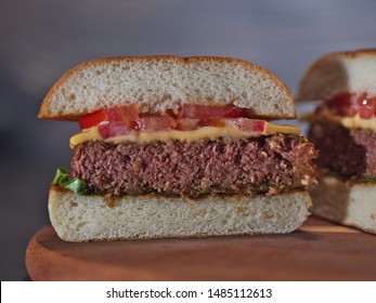 Closeup On Vegan Plant Based Burger Cut In Half Served On Wooden Tray