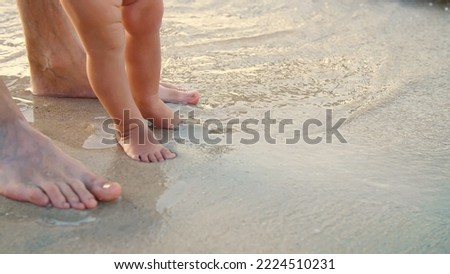 close-up, on wet sand, there are male and children's feet. a wave comes in. Vacation on ocean beach, Summer holiday. High quality photo