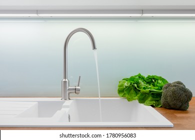 Close-up On White Sink With Simple Silver Kitchen Faucet Turned On