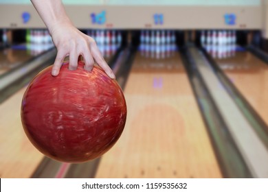 Close-up On Woman Hand Holding Bowling Ball Against Bowling Alley