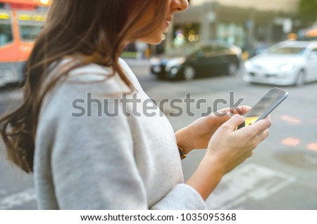 Close-up on woman hands holding smartphone in the center of the city.