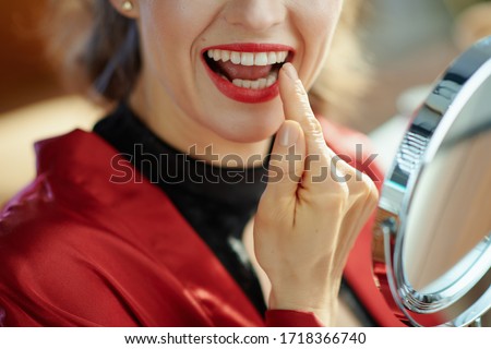 Closeup on woman in the living room in sunny day looking in mirror and checking teeth.