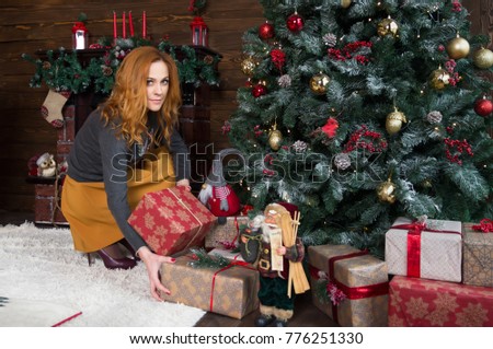Closeup on woman putting christmas present box under christmas tree. New Year and Christmas celebration. Christmas tree, gifts, fireplace on background