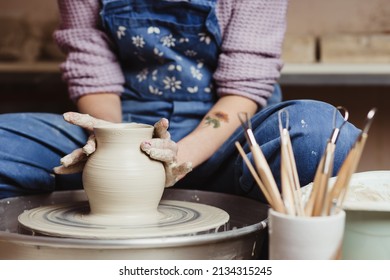 Close-up on woman with tattooed hands working on pottery wheel and making a pot. - Powered by Shutterstock