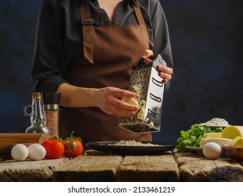 Close-up. On A Wooden Table, A Professional Chef Grates Cheese. Ingredients For Making Salad, Pie, Pasta, Pizza. Restaurant, Hotel, Home Cooking, Food Blog.