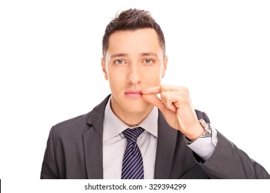 Close-up on a young businessman holding his hand on his lips symbolizing shut mouth isolated on white background