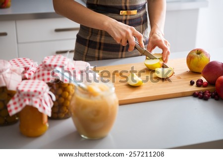 Closeup on young housewife cutting apple for jam