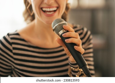 Closeup On Young Woman Singing With Microphone In Loft Apartment