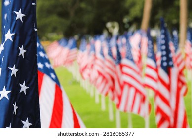 Close-up of one American flag with multiple flags flown in the background to honor those that served.