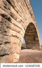 Closeup of one arch of the Stone Arch Bridge in Minneapolis, a former railroad bridge turned into a pedestrian and bicycling bridge. The dark streaks on the stones are water marks.