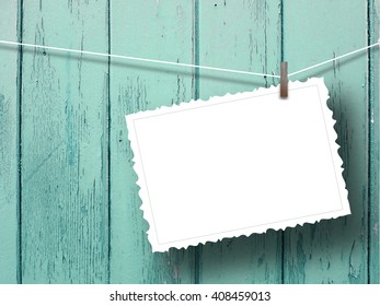 Close-up of one blank postcard frame hanged by peg against aqua wooden background