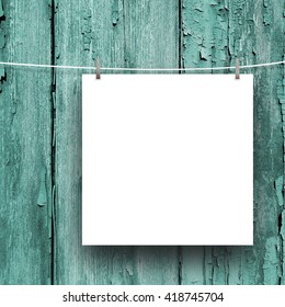 Close-up of one blank square frame hanged by pegs against aqua weathered wooden boards background