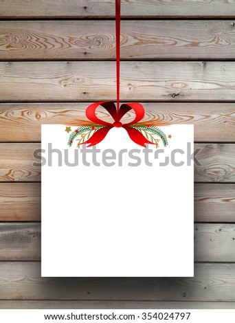 Close-up of one empty square paper sheet frame with Xmas ribbon decoration on brown wooden boards background
