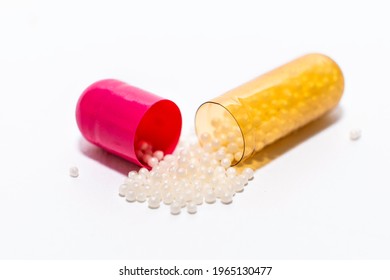 Close-up one opened pink yellow soft capsule pill with powder on white background. medicine supplement vitamin