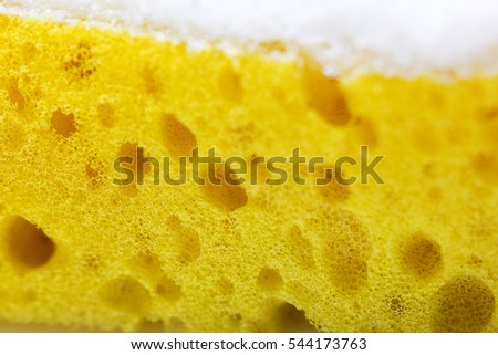 A close-up of one yellow corner of a urethane sponge with a top white layer used for more intense dish scrubbing
