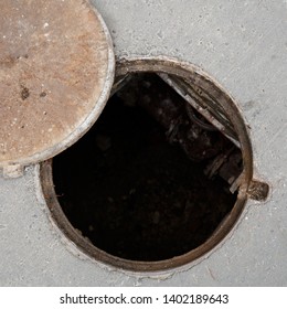 Closeup of an open manhole with a cover on the asphalt road. Top view of the sewer. Danger to people. Underground pipeline repair.