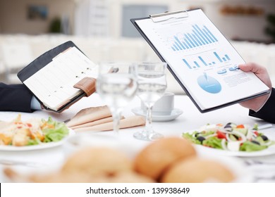 Close-up of open notepad and business document in male hands during business lunch
