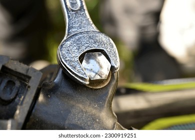 A close-up of an open-end wrench used to tighten a bicycle handlebar bolt.