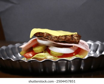 A close-up of an open-faced burger with lettuce, onion, tomato, pickles, deli meat, and a burger patty topped with mayonnaise and mustard. The final step before placing the top bun, ideal for food  - Powered by Shutterstock