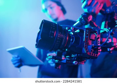 Close-up of operator using professional camera during shooting with director controlling the process