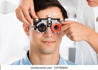 Close-up Of An Optometrist Checking Male Patient Vision With Trial Frame At Eye Clinic