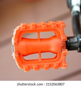 A Closeup Of An Orange Bike Pedal On A Blurred Background